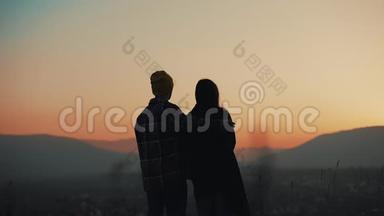 恋爱中的年轻夫妇在山上欣赏日落的剪影。 假期，旅行，浪漫，求婚